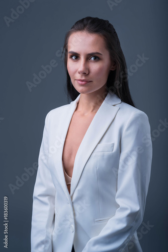 Business style. Brunette concentrated pensive woman standing on the dark background while staring at the camera and  getting ready for business deal 