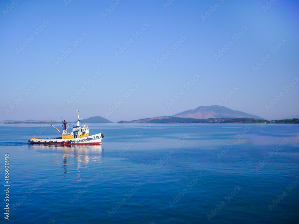 small colorful fishing boat in calm water with blue sky