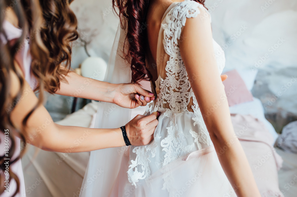 Bridesmaid preparing bride for the wedding day Bridesmaid preparing bride for the wedding day