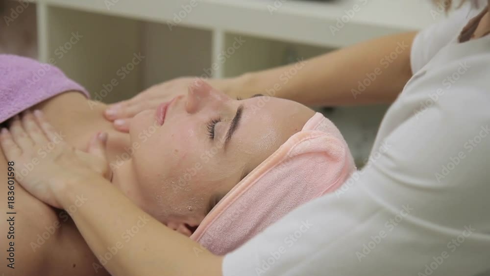The female cosmetologist massages the face, breast and neck of the client in spa salon The female cosmetologist massages the face, breast and neck of the client in spa salon