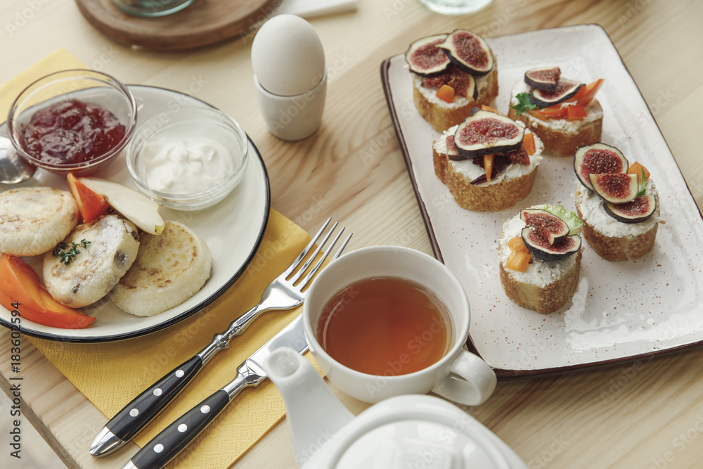 close-up view of tasty healthy breakfast with cheesecakes fritters and canapes with figs on table close-up view of tasty healthy breakfast with cheesecakes fritters and canapes with figs on table