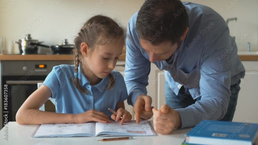 Father helping daughter with homework at home. Father helping daughter with homework at home.