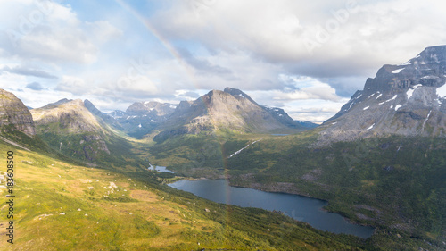 Beautiful sunny day in the mountains. Rainbow shining over mountain valley in Norway.