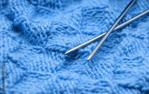 Detail of woven handicraft knit woolen design texture and knitting needle. Fabric blue background © nata777_7
