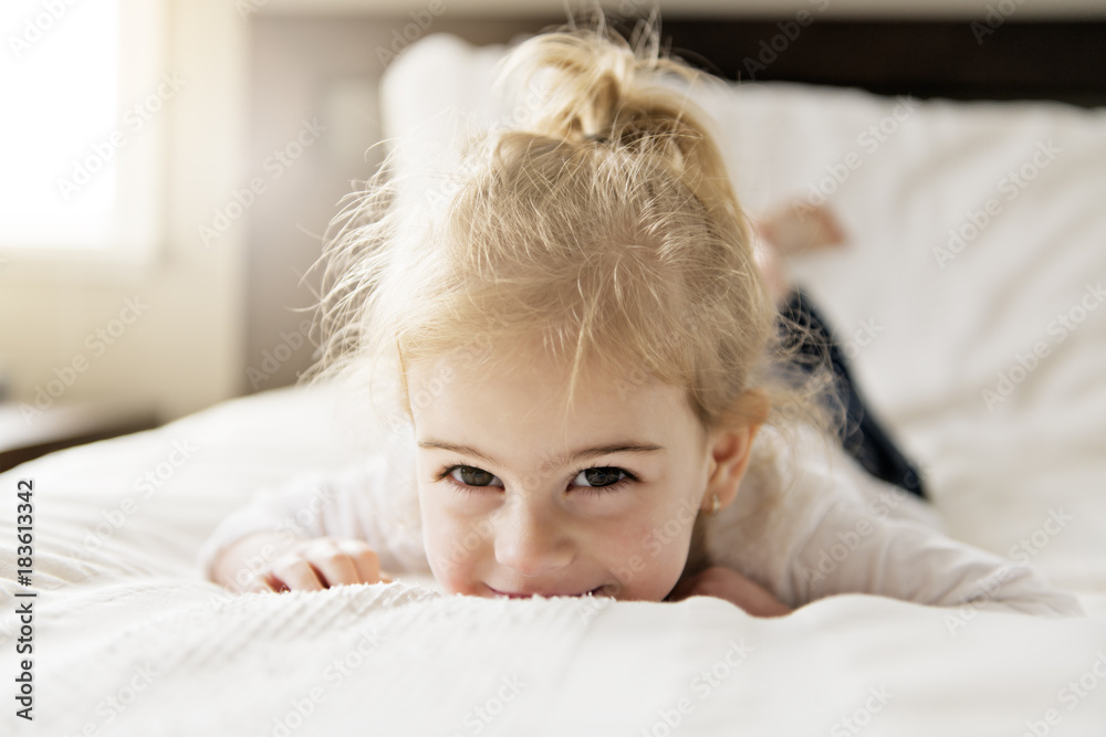 young daughter two years old relaxing in bed, positive feelings