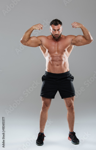 Full length portrait of a muscular concentrated shirtless male bodybuilder