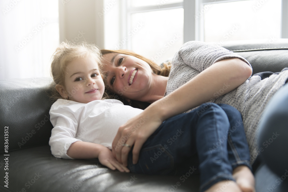 Happy mother with her daughter on the sofa in the living room at home Happy mother with her daughter on the sofa in the living room at home