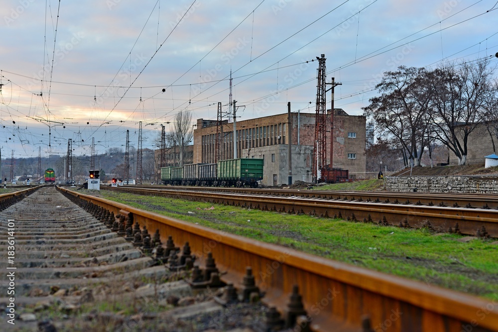 Railway station against beautiful sky at sunset. Industrial landscape with railroad, colorful cloudy blue sky. Railway sleepers. Railway junction. Heavy industry. Cargo shipping. Travel background