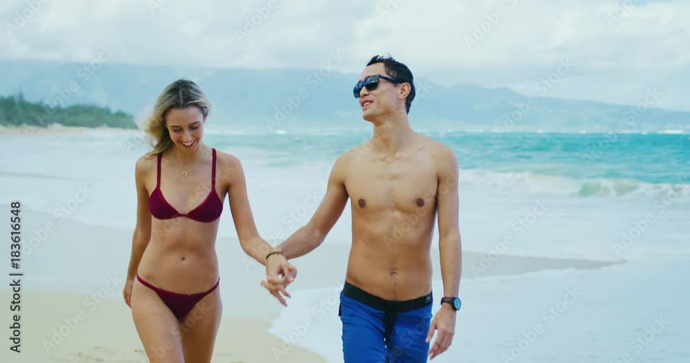 Attractive fun young couple walking down the beach Attractive fun young couple walking down the beach