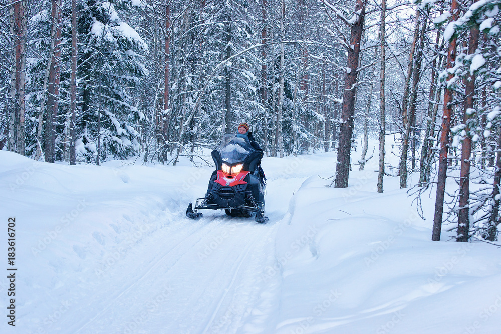 Woman riding snowmobile at winter forest  Rovaniemi Finland