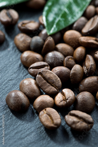 roasted coffee beans and leaves on a dark background, vertical, close-up