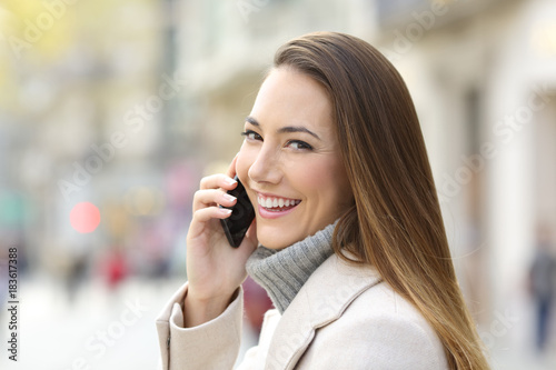 Happy girl calling on phone in winter and looking you