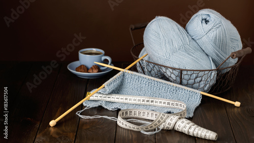 Knitting from light blue yarn. Cup of coffee and chocolates.