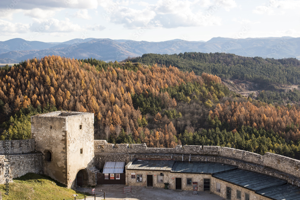 The courtyard of a medieval castle with tower on the background of forest and mountains