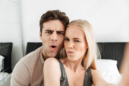 Funny attractive lovers making selfie and grimacing in the morning