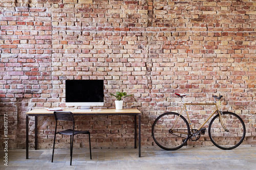 Workspace and bicycle at brick wall in office photo