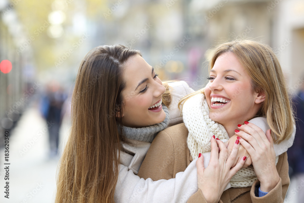 Two happy friends joking on the street in winter Two happy friends joking on the street in winter