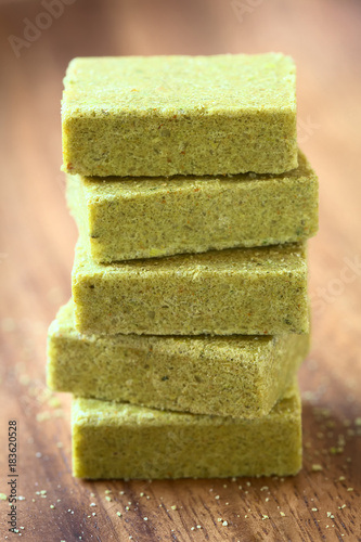 Vegetable bouillon, stock or broth cubes on wooden plate, photographed with natural light (Selective Focus, Focus on the front upper edges of the top cubes)