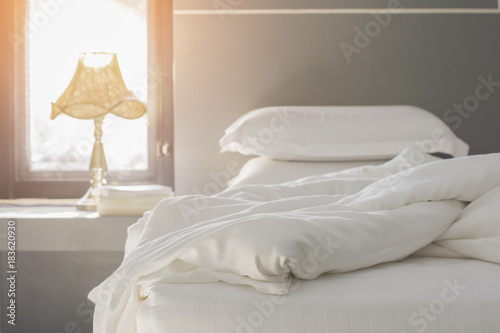 Bed maid-up with clean white pillows and bed sheets in beauty room. Close-up. Lens flair in sunlight.Close up white bedding sheets and pillow, Messy bed concept