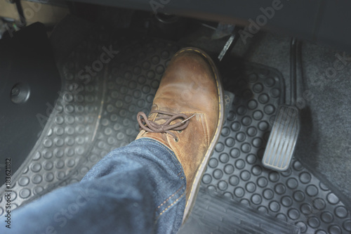 Foto Driver foot in brown leather boot pressing brake pedal inside car interior