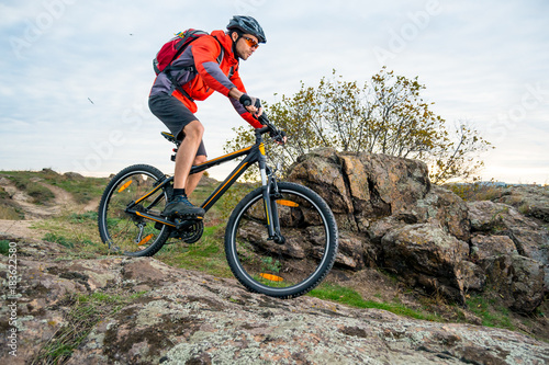 Cyclist in Red Riding the Mountain Bike down Autumn Rocky Trail. Extreme Sport and Enduro Biking Concept. © Maksym Protsenko