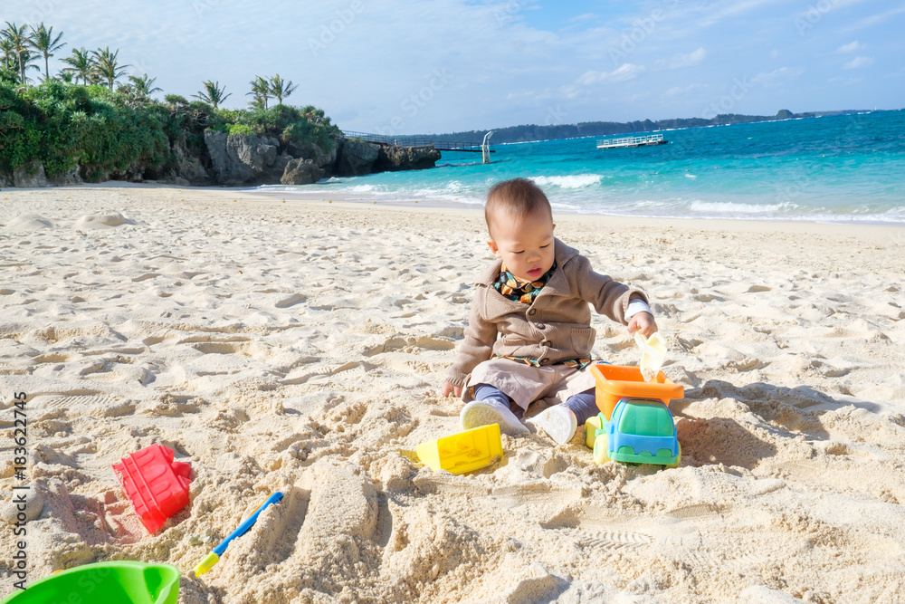 Cute little Asian 1 - 2 years old toddler baby boy sitting & playing colorful toys on beautiful sandy tropical beach Okinawa, Japan. Family travel, water outdoor activity on beach vacation concept Cute little Asian 1 - 2 years old toddler baby boy sitting & playing colorful toys on beautiful sandy tropical beach Okinawa, Japan. Family travel, water outdoor activity on beach vacation concept