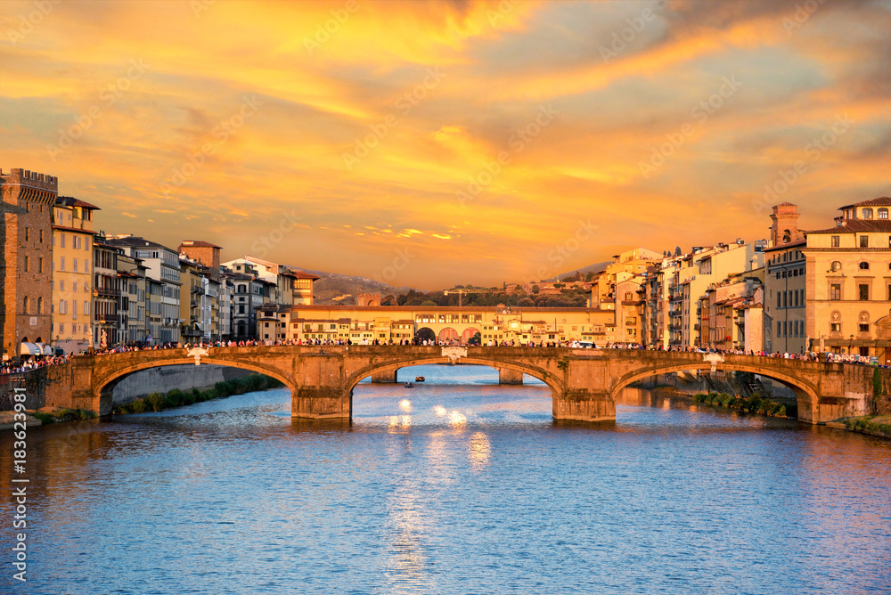 Fototapeta premium Piękny widok na miasto ze słynnym średniowiecznym kamiennym mostem Ponte Vecchio nad rzeką Arno we Florencji o zachodzie słońca. Miejsce pielgrzymek dla turystów.