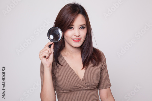 Young Asian woman with a magnifying glass.