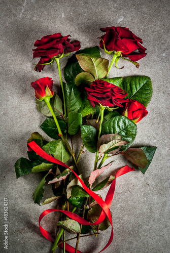 Holiday background, Valentine's day. Bouquet of red roses, tie with a red ribbon. On a gray stone table