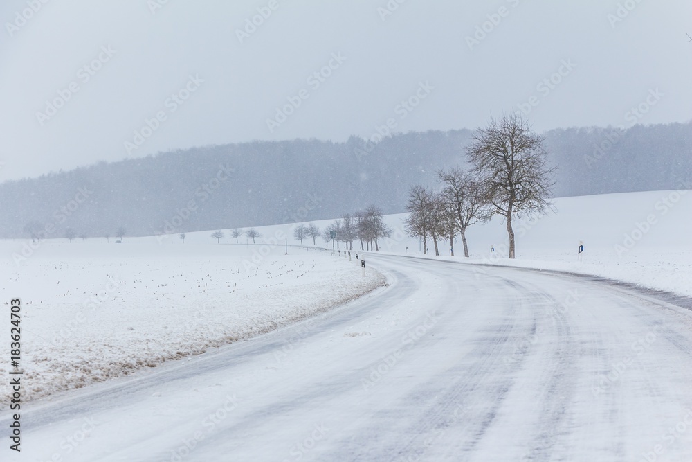 Eisige glatte Winter Straße mit Schnee wartet auf Winterdienst. Die Fahrbahn ist weiß glatt verschneit. Vorsicht vor Unfall durch Schneesturm und schlechte Sicht. Wetter zur Weihnachten Jahreszeit