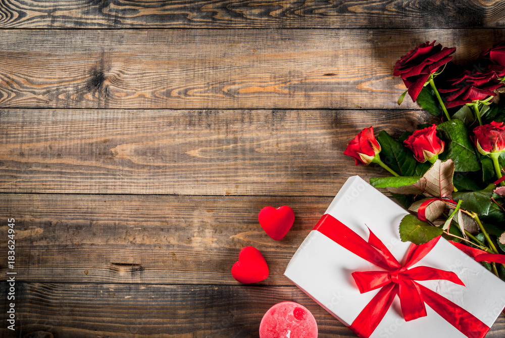 Holiday background, Valentine's day. Bouquet of red roses, tie with a red ribbon, with wrapped gift box. On wooden table, copy space top view Holiday background, Valentine's day. Bouquet of red roses, tie with a red ribbon, with wrapped gift box. On wooden table, copy space top view