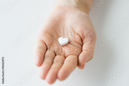 close up of hand holding medicine heart pill