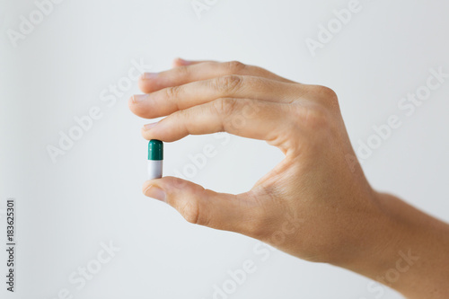 close up of hand holding capsule of medicine