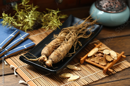 .ginseng in black plate on wooden table photo