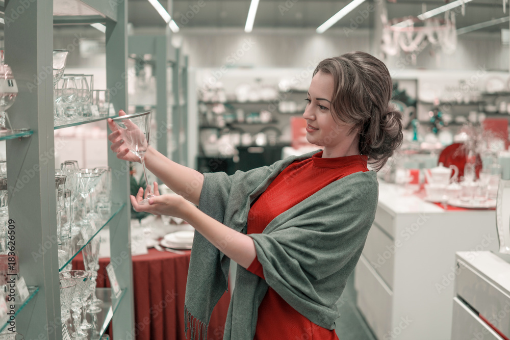 female customer choosing crystal glasses utensil dishes in the supermarket mall female customer choosing crystal glasses utensil dishes in the supermarket mall