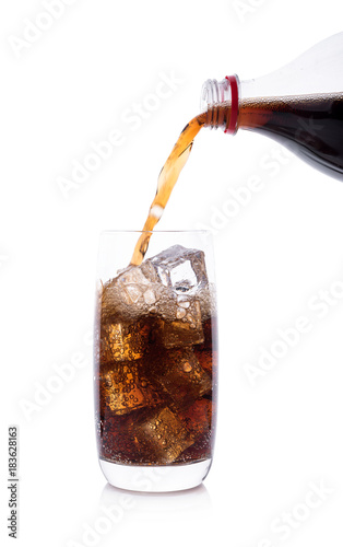 Bottle pouring Cola in drink glass with ice cubes
