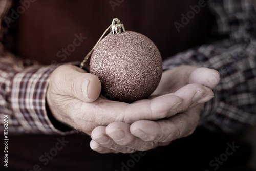 Obraz na plátně old man with a christmas ball in his hands