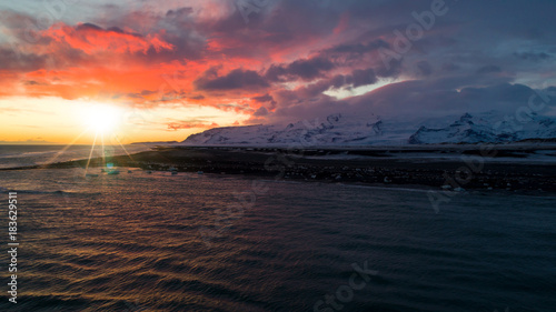 Aerial view of beautiful colorful sunset landscape on black sand beach with icebergs, Iceland.