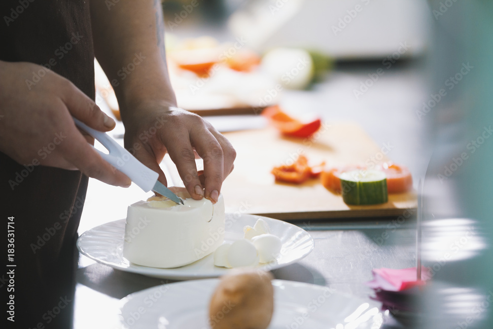 Chef cut the cheese feta for salad in commercial kitchen
