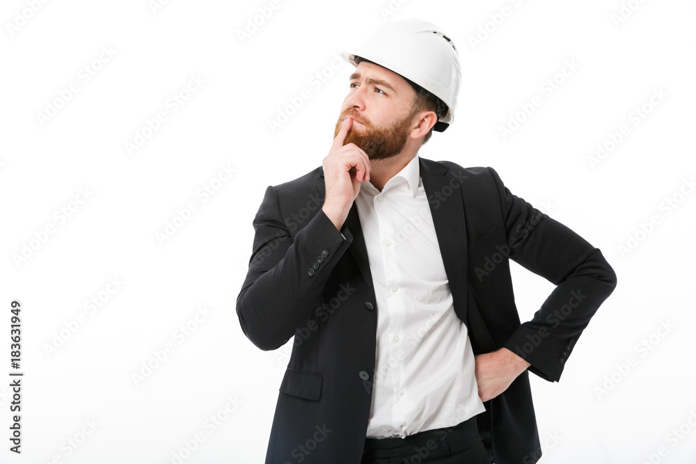 Thoughtful bearded business man in protective helmet looking away Thoughtful bearded business man in protective helmet looking away