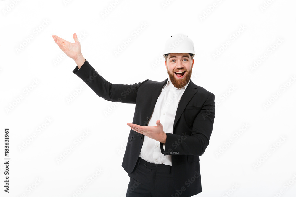 Cheerful bearded business man in protective helmet pointing away Cheerful bearded business man in protective helmet pointing away