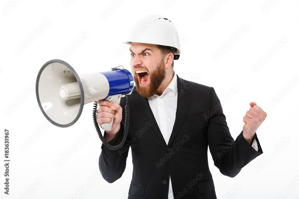 Angry bearded business man in protective helmet screaming in megaphone Angry bearded business man in protective helmet screaming in megaphone