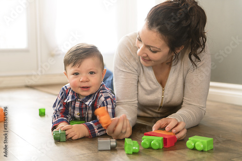 Mother and child boy building from toy blocks at home