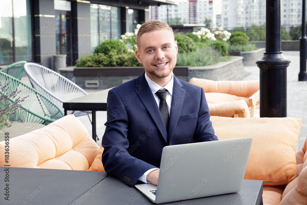 Handsome man in suit sitting with his laptop outdoors Handsome man in suit sitting with his laptop outdoors
