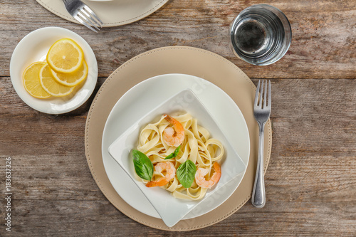 Plate of tasty pasta with shrimps on wooden table  top view