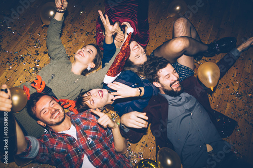 Group of friends having fun on a floor, celebrating New Year 