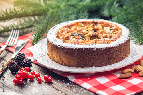 Homemade Christmas or New Year holiday berry pie with nuts on wooden table background. Concept of festive desserts