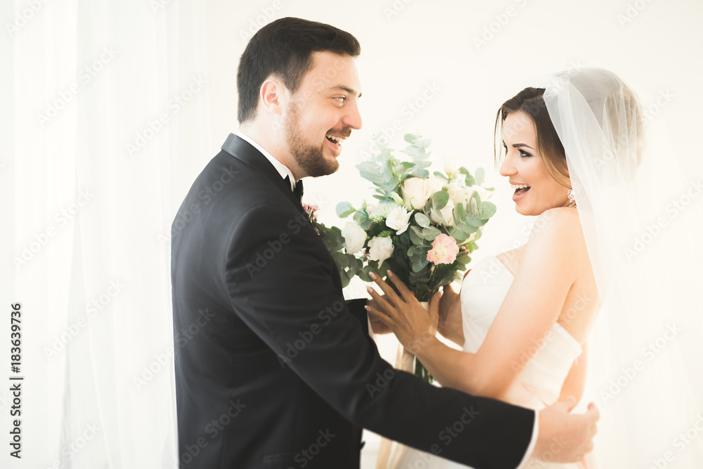 Wedding photo shoot of the newlyweds couple in a beautiful hotel posing near window Wedding photo shoot of the newlyweds couple in a beautiful hotel posing near window