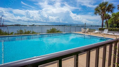 A fenced in pool located next too a river 