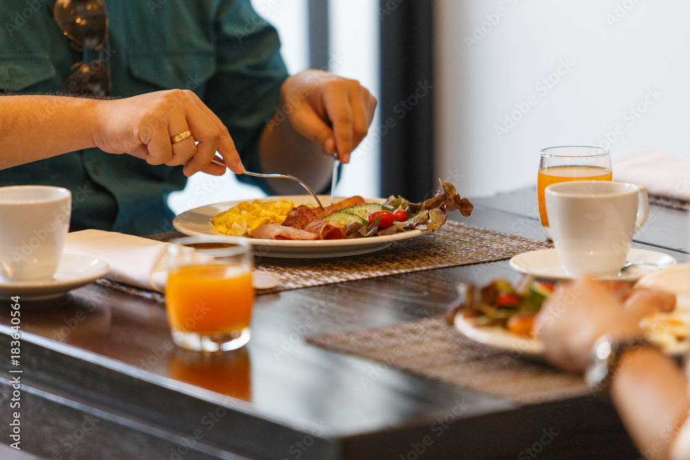 A couples, women and men seating to eat breakfast and drinks, with both orange juice and coffee on the table